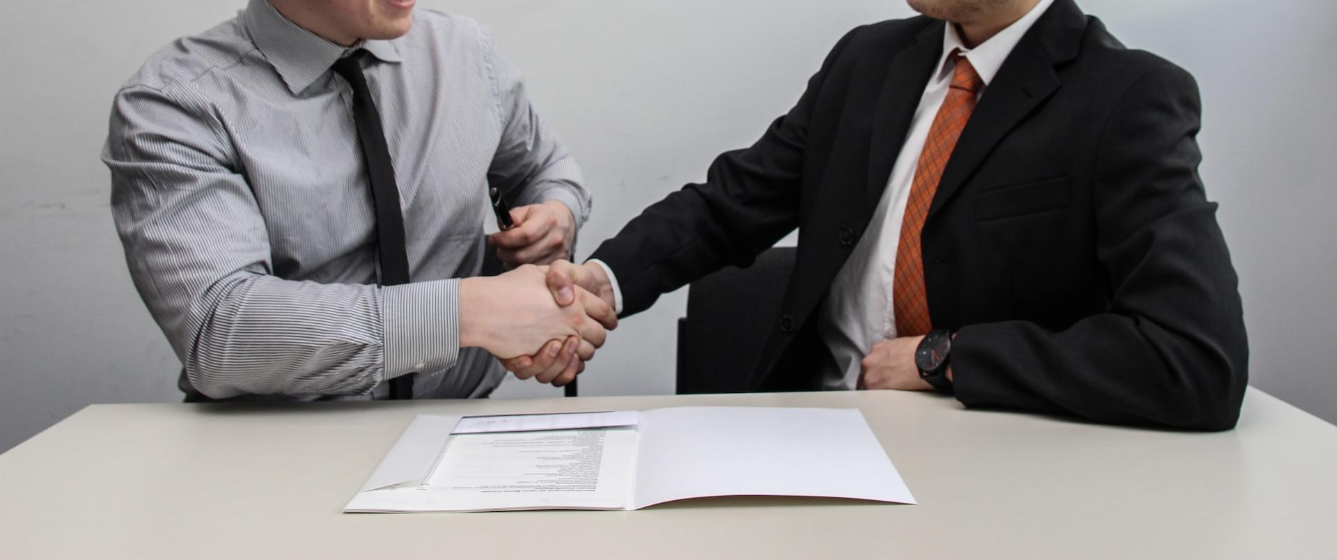 two men facing each other while shake hands and smiling